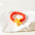 Close-up of handmade orange beaded ring with yellow starfish accent on a stone base - Yellow Sea Star Style (31026-ring-red)