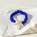 Detail of blue beaded ring with a cream starfish charm on a rustic white stone - Cream Sea Star Style (31026-ring-rb)