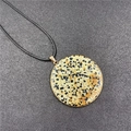 Colgante redondo de piedra dálmata con borde dorado y cordón negro sobre fondo gris - Jaspe dálmata