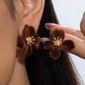 Macro view of brown velvet flower earrings with gold center worn on a model's ear - Brown Flocked Flower Style (29961-ear-brown-EP)