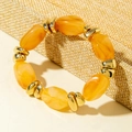 Macro detail of amber acrylic beads with gold metal spacers on a textured fabric - Yellow Marble Pattern Bead Bracelet (31597)