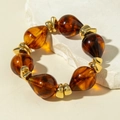 Close-up of amber resin teardrop beads with gold metal spacers on white stone - Amber Teardrop Large Grain Bracelet (31601)