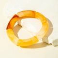 Close-up of retro acrylic curved tube bracelet with translucent amber texture on stone - Amber Texture Segmented Elastic Bangle (31609)