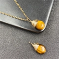 Tiger eye teardrop pendant necklace with gold wire wrapping on black surface - Tiger's Eye