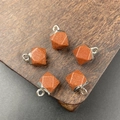 Octagonal faceted goldstone crystal pendants with silver metal loops on dark wood base - Synthetic Goldstone