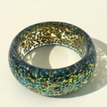 Macro shot of colorful iridescent glitter fragments inside a wide resin chunky bangle - Dark Blue