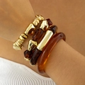 Dettaglio di bracciali in resina ambrata e CCB oro opaco indossati su un polso - Set da 4 Pezzi Contrasto Oro Ambra (31623-bra-brown-EP)