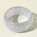 Detailed view of colorful resin bangle with sparkling glitter and artistic shadows - White