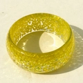 Detail of yellow resin bangle featuring sparkly glitter inclusions and a wide glossy finish - Yellow