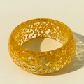 Macro detail of wide resin bangle featuring sparkling gold foil chips and clear texture - Orange