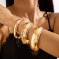 Dettaglio di un set di tre ampi bracciali rigidi dorati lucidi indossati sul polso - Set da 3 Pezzi Oro (27804-bra-G-EP)