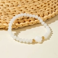Detail of colorful crystal beaded bracelet featuring white clover charm and gold accents - White