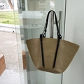 Bolso tote de paja tejido a mano con correas negras colgado en una puerta de vidrio - Bolso Tote Tejido (4848710348890) / Tostado