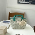 Gesteppte florale Lunchtasche mit grünen Griffen und Quaste auf einem Tisch - Grünes Blumenmuster