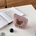 Detail of pink fleece makeup bag with happy bear embroidery on a white desk surface - Pink