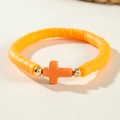 Gros plan d'un bracelet en perles heishi orange avec un petit pendentif croix dorée - Orange