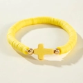 Vue détaillée du bracelet en perles Heishi jaunes avec un pendentif croix dorée - Jaune