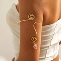 Detalle de brazalete dorado con diseño de espiral y colgante de piedra preciosa púrpura - Oro-Piedra Púrpura