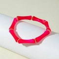 Pink acrylic bamboo tube stretch bracelet with gold spacers shown on a white display - Rose Red