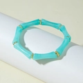Detail of turquoise bamboo tube stretch bracelet with gold accent beads on a white display - Lake Blue