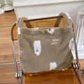 Detail einer braunen Lammwoll-Tasche mit weißem Cartoon-Muster auf orangefarbenem Muster auf Stuhl - Khaki Buchstaben Weißer Hund Umhängetasche
