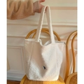 Détail d'un sac cabas en peluche beige avec une petite étiquette bleue sur le devant - Blanc Cassé