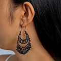 Close-up of black bohemian hollow-out crescent earrings with beads worn by a model - Black Hollow Crescent Round Bead Tassel Style (9199-black)