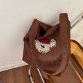 Dunkelbraune Cord-Einkaufstasche mit Bärenstickerei auf einem orangefarbenen Stuhl - Baskenmütze Hund Karamell Cord Stil