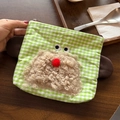 Detail of green plaid makeup bag featuring a cute fuzzy monster face on a wooden desk - Puppy Green Plaid