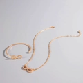 Detail view of a gold infinity jewelry set with sparkling crystals on necklace and cuff - Infinity Pendant Necklace Bracelet Set (P-564) / Gold