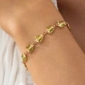 Detalle de una pulsera de mariposa dorada con gemas verdes en la muñeca de la modelo - Pulsera Mariposa Verde (30639-bra-green-EP) / Dorado