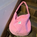 Nahaufnahme der rosa Plüsch-Hobo-Tasche mit gewebtem Etikett auf dunkler Holztreppe - Rosa Stil