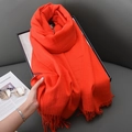 Soft orange-red cashmere-feel scarf with tassels laid on leather sofa with magazine - Orange Red