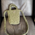 Détail du mini sac cabas en peluche verte avec bouton à carreaux sur une chaise en cuir - Vert Mousse