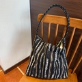 Gestrickte Schultertasche mit schwarz-weiß-braunen Streifen auf Holzstuhl - Blau Weiß und Gold Gewebte Streifen