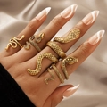 Five-piece gold snake ring set in vintage punk style worn on a hand over satin - Snake Shape Design (18643) / Five-Piece Set / Gold