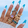 Set di 5 anelli dorati con motivi a serpente e cristallo a cuore viola su mano modella - Stile Cuore di Serpente con Gemma Viola (19656-suit)