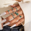 Gros plan sur les bagues géométriques vert émeraude en argent, portées avec un blazer blanc - Style Griffes Géométrique Vert Émeraude Argent (28700)