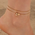 Close-up of double-layered gold anklet with A-letter and heart charm on a beach - Double Layer Letter A & Heart Style (30935-ank-G-EP)