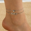 Detail of silver double-layer anklet with heart and infinity charms on a sandy beach - Double Layer Heart & Infinity Symbol Style (p-564-ank-S)