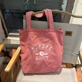 Detail of vintage pink canvas tote bag with white ethnic prints on an outdoor chair - Carmine Pink