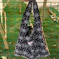 Black canvas tote bag with white daisy embroidery and a pink slogan label - Black