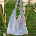 Light blue tote bag with white floral embroidery and a heart tag hanging outdoors - Light Blue