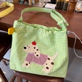 Grüne karierte Kordelzug-Umhängetasche mit Hunde-Aufnäher und gelben Trägern - Grüner Gingham-Hund mit Apfel-Design