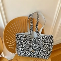 Leoparden-Canvas-Tasche mit goldenem Logo-Tag auf einem modernen Holzstuhl - Weiße Wende-Einkaufstasche Mit Leopardenmuster Und Breitem Trageriemen
