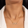 Gold infinity pendant necklace with micro-pave zircons worn on a chic white suit - Gold Infinity Rhinestone Necklace (P-564)