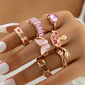 Parure de 7 bagues dorées avec gemmes roses, papillons et étoiles portées sur la main - Style Pierre Précieuse Papillon Doux (22642-gold)