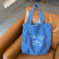 Blue denim canvas tote bag featuring white paisley print on a brown leather sofa - Vintage Blue