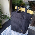 Minimalistische schwarze Faltentasche mit Vordertasche und breitem Griff auf Holzstuhl - Schwarz plissierter Stil