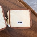 Square cream makeup bag with brown trim and HOPE woven label on a wooden tray - Small / Off White